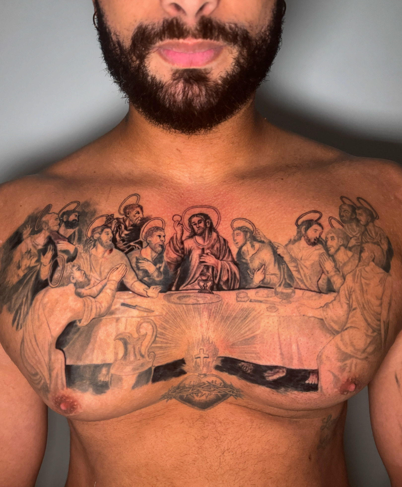Black-and-grey Last Supper chest piece with a sacred heart below