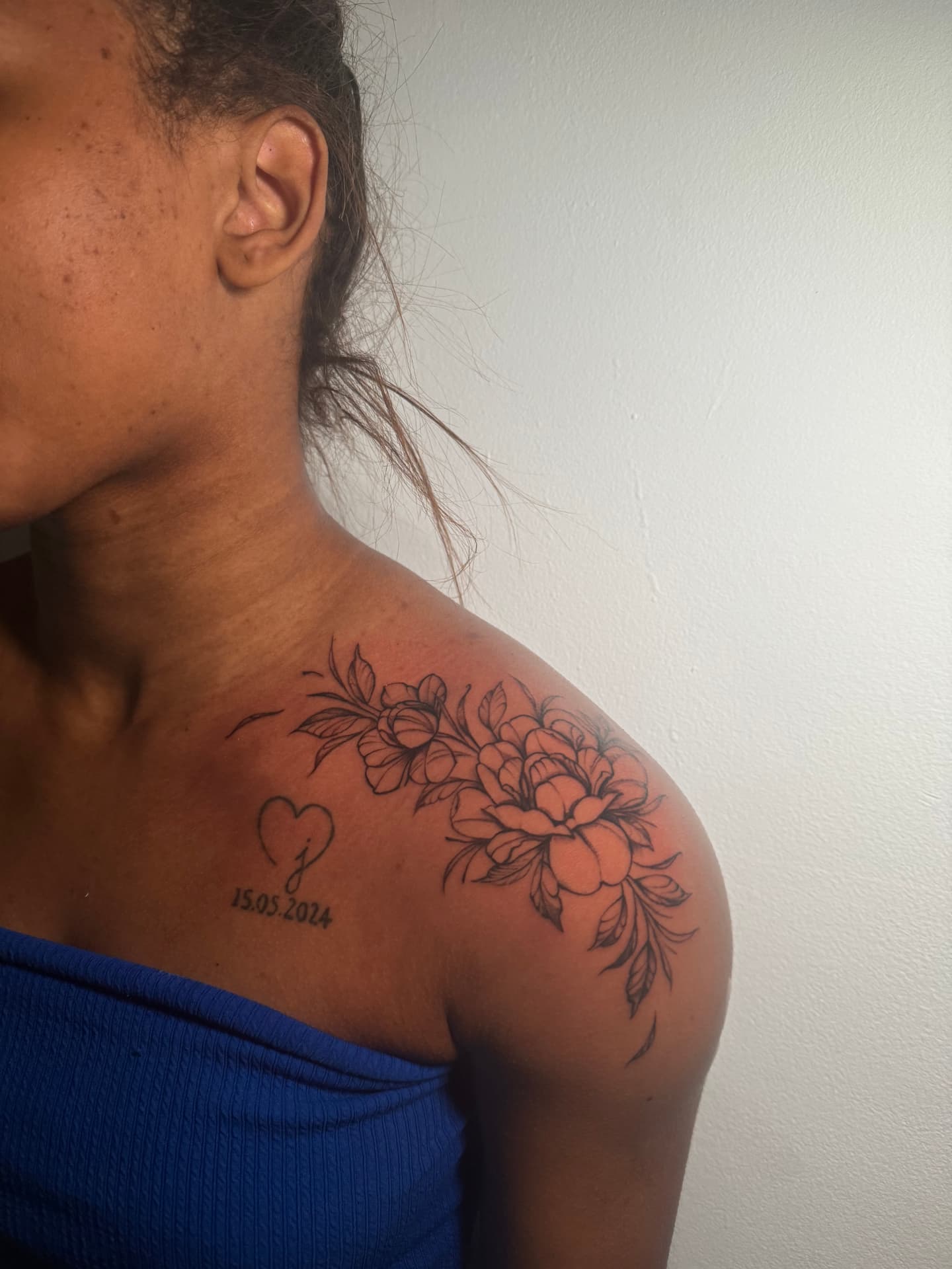 Black-and-grey floral shoulder tattoo with a heart and date